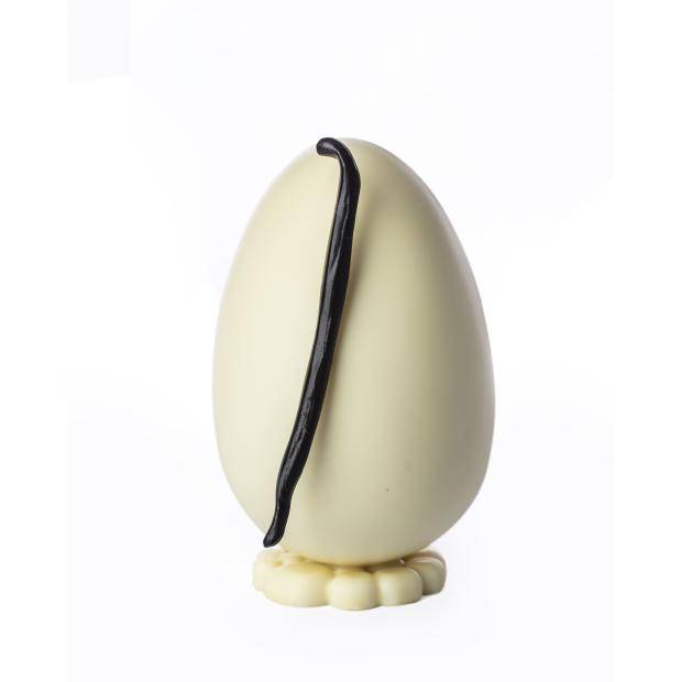 ovo de chocolate branco em pé de frente com fava de baunilha grudada na casca